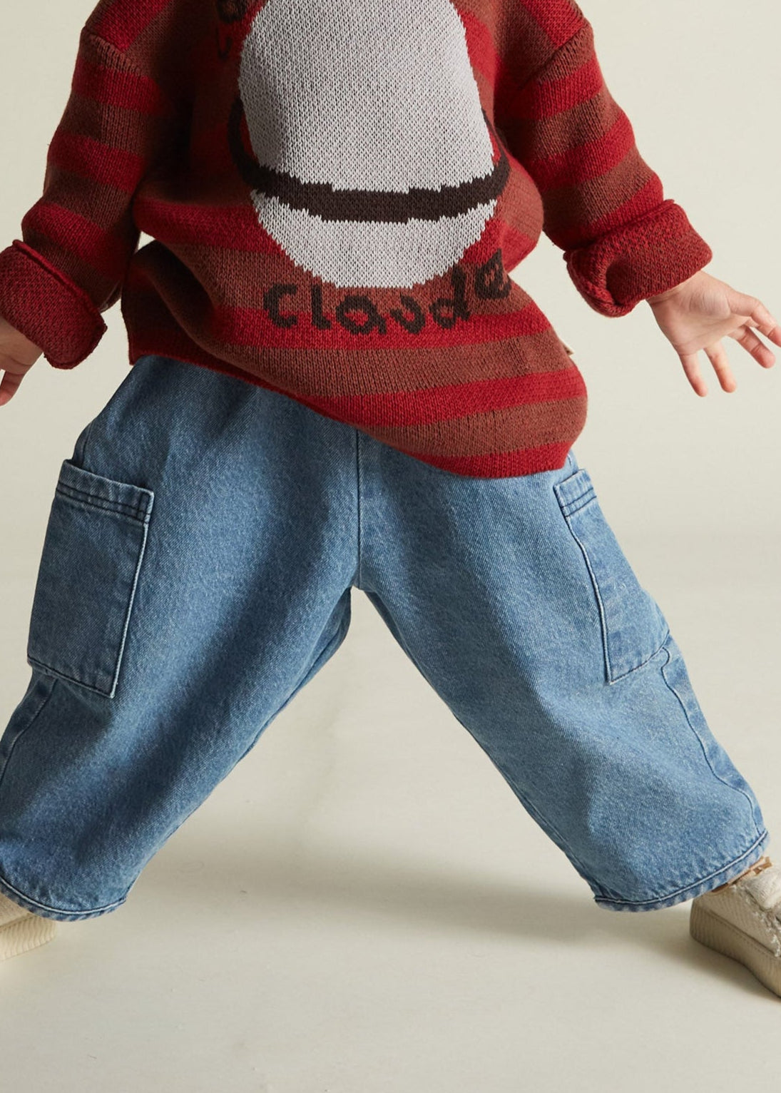 Child wearing a red sweater with a graphic design on a plain background